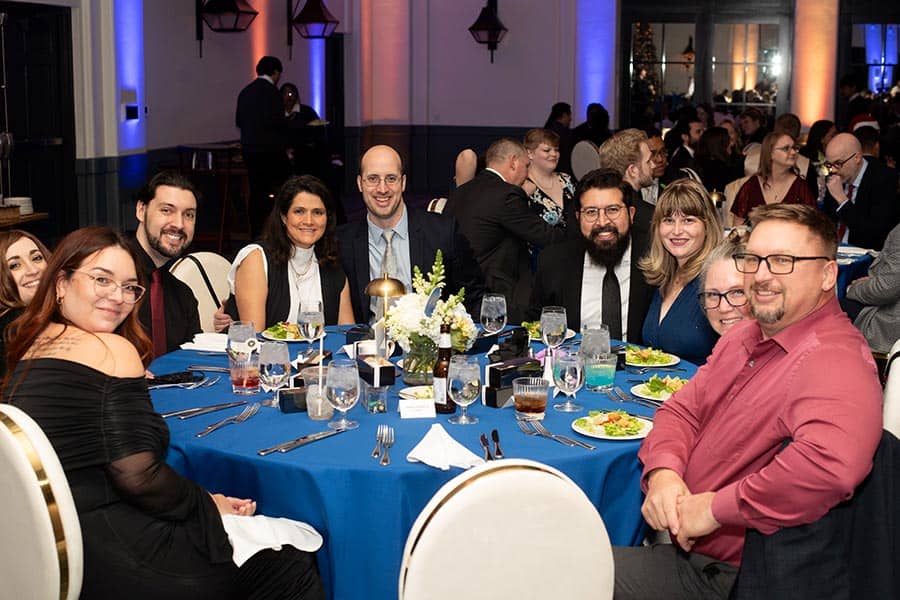 A group of Vertech Christmas party-goers relaxes at a dining table.