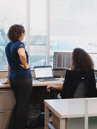 Coworkers reviewing work on a computer screen.