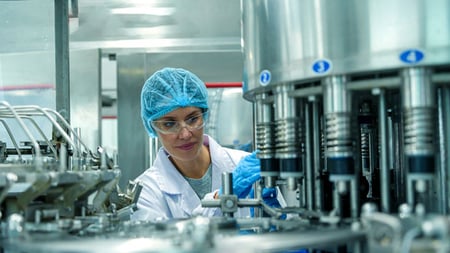 A technician inspects equipment at a beverage plant.