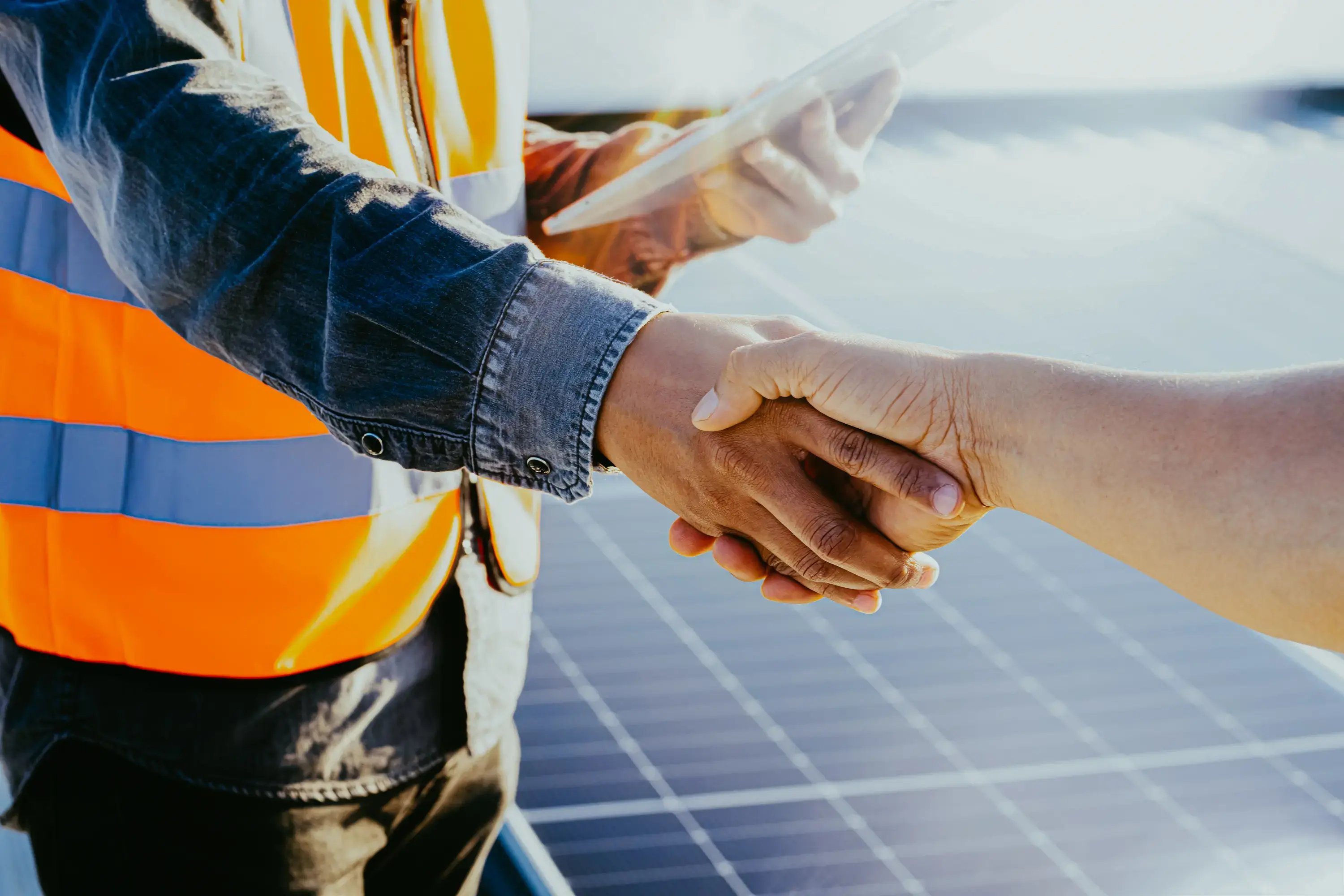 Business partners shaking hands while standing in a solar field