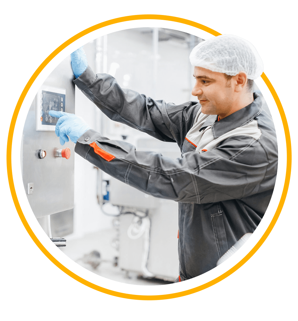 A dairy plant employee wearing gloves and a hairnet presses buttons on plant machinery. 