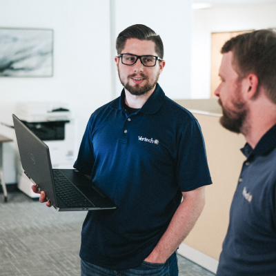 Two Vertech team members, one holding a laptop, chat in the Nashville office.