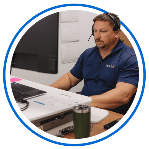 A Vertech team member wearing a phone headset sits at a desk, ready to assist.