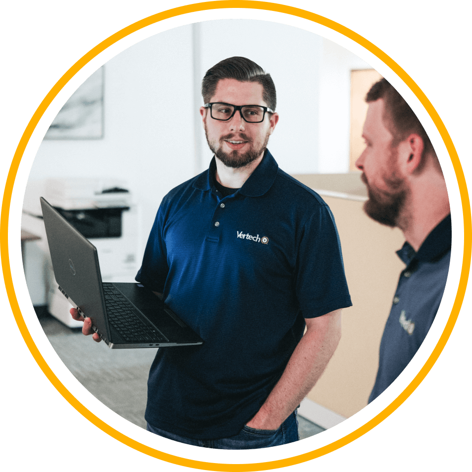 Two Vertech team members, one holding a laptop, chat in the Nashville office.