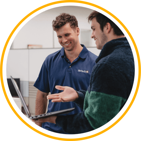 Two Vertech team members, one holding a laptop, chat in the Nashville office.