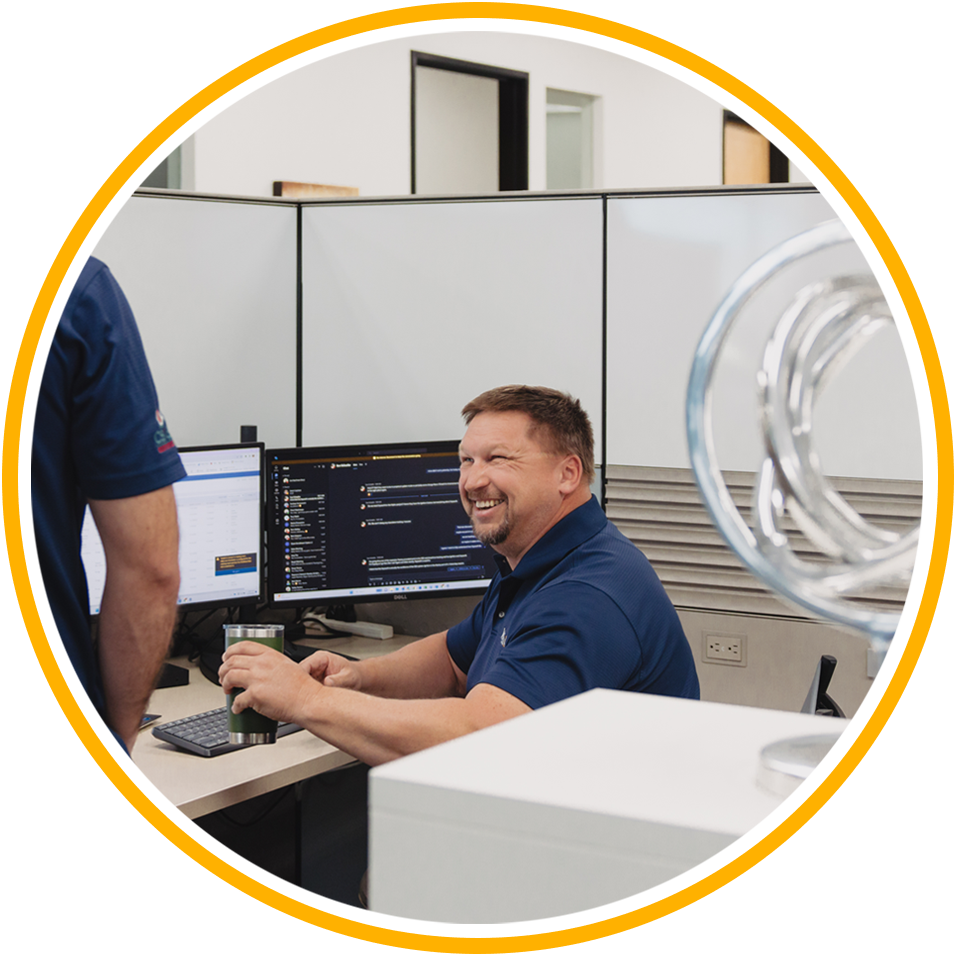 man smiles warmly at colleague while sitting at desk