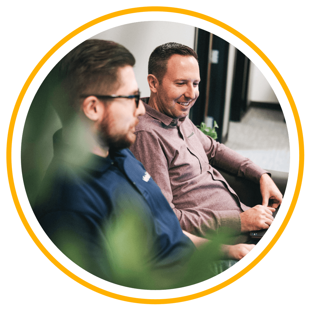 A Vertech team member sitting next to a smiling client as they work together.